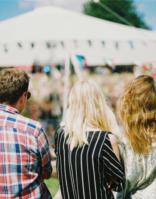 Three young adults sitting down watching concert