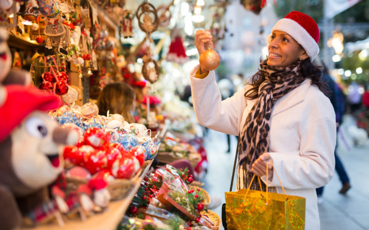 Woman shopping for gifts at outdoor Christmas market.
