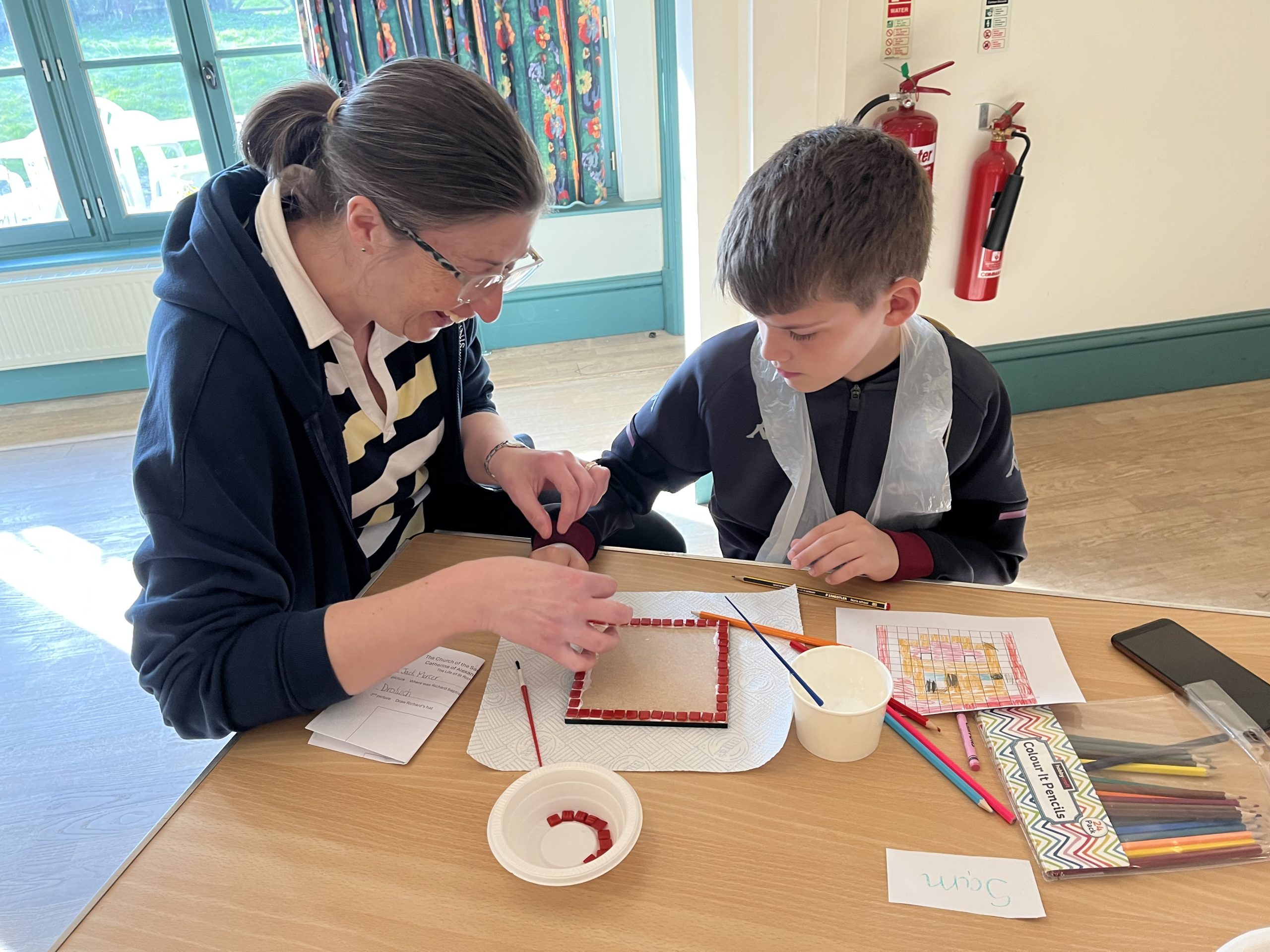 An adult and child working together to make a mosaic.